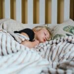 a little girl sleeping in a bed with a blanket