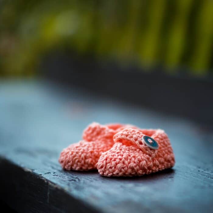 pair of baby's pink knit shoes on bench