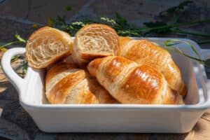 a white dish filled with croissants sitting on top of a table